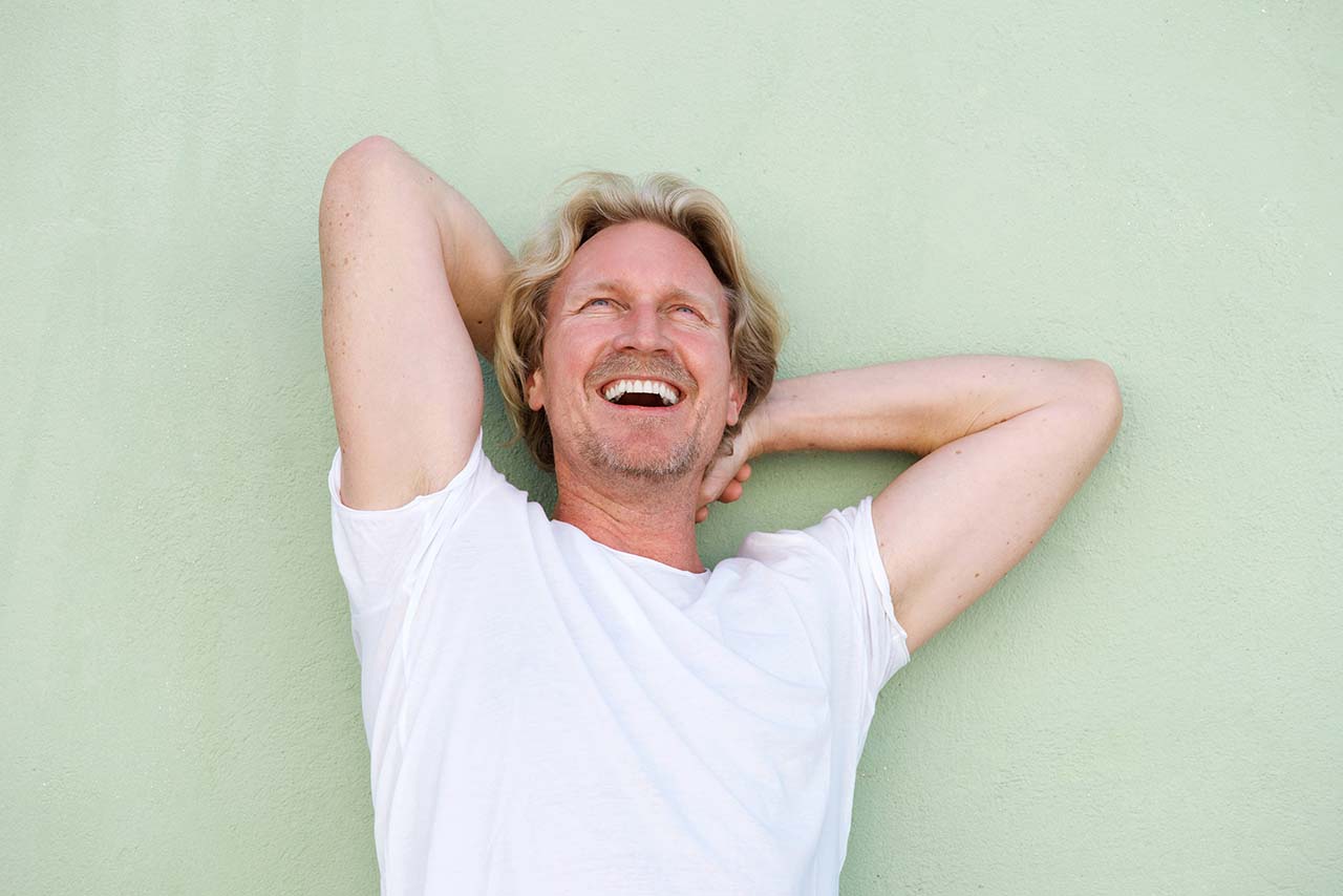 middle aged guy laughing with hands behind head